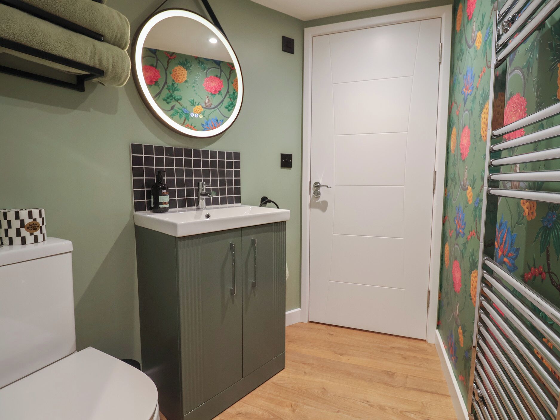 A bathroom with a white sink, a mirror, a toilet, and a shower area.
