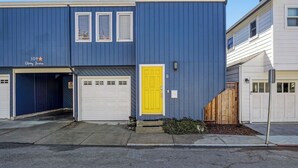 Un bâtiment à deux étages, avec une façade bleue, une porte jaune et un garage.