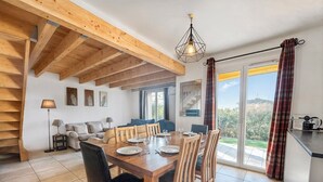 Een eetruimte met een houten tafel en stoelen, een trap en uitzicht op het landschap.
