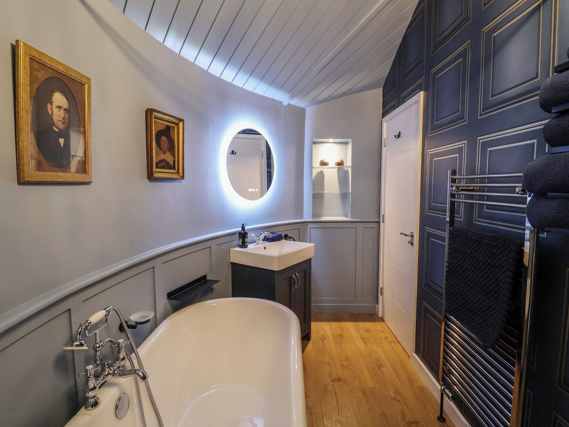 A bathroom with a bathtub, a sink, a mirror, and a door with a towel rack.