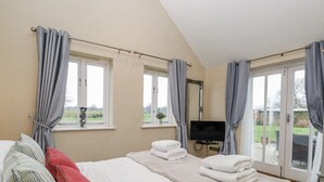 Un dormitorio con cama, televisor y vistas al exterior.