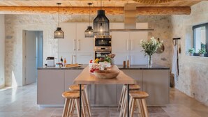 Een moderne keuken met een centraal eiland, houten krukken en hanglampen.