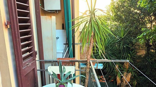 A small balcony with a table and chairs, surrounded by potted plants and a metal railing. - The Florence Nest (Firenze)