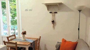 A small, cozy room with a dining table and chairs, a sofa with striped cushions, a hanging plant, and a lamp. - The Florence Nest (Firenze)