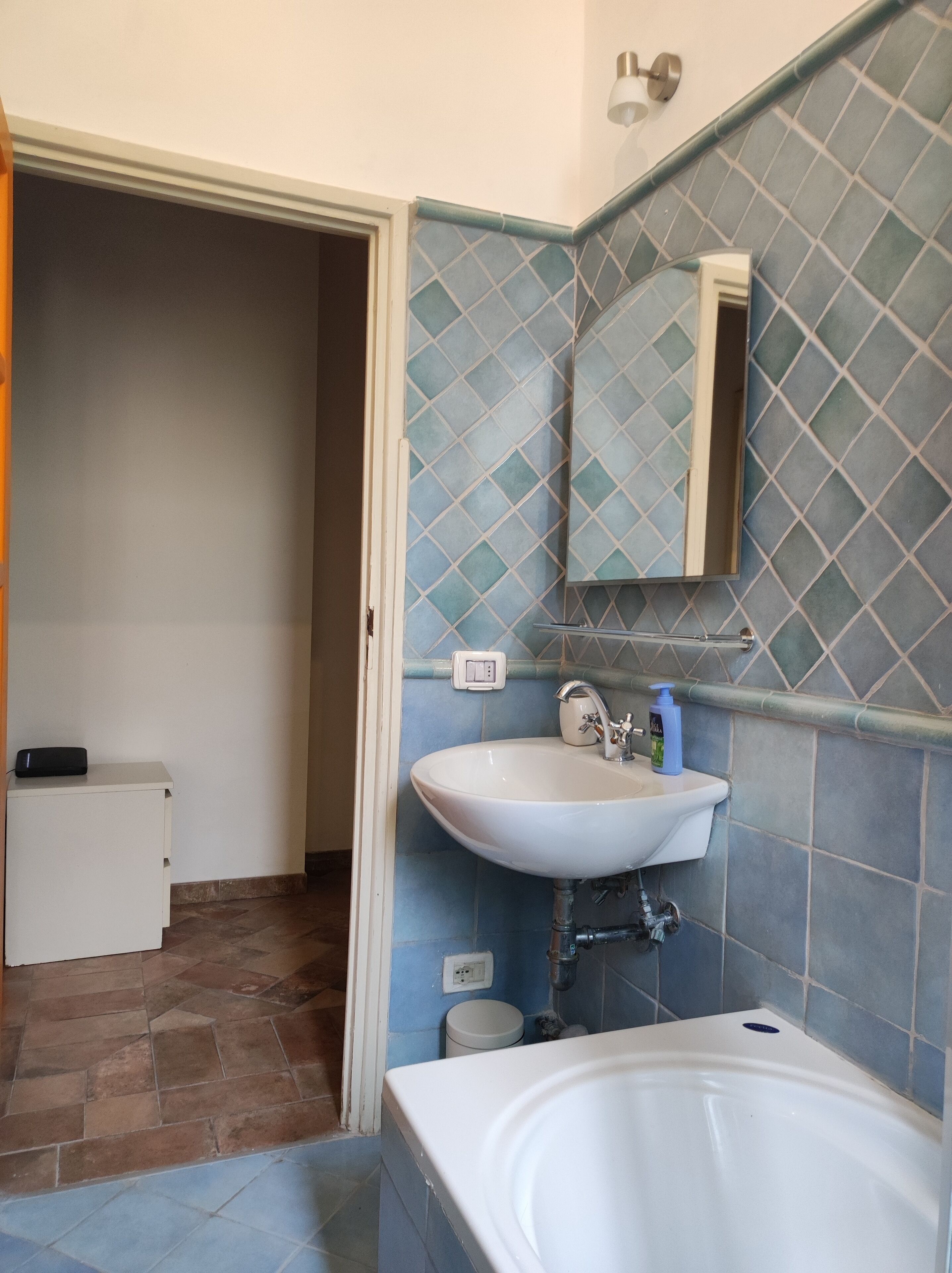 Un baño con lavamanos blanco, un espejo y una bañera.