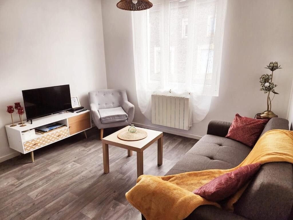A living room with a sofa, a television, a chair, a small table, and a radiator.