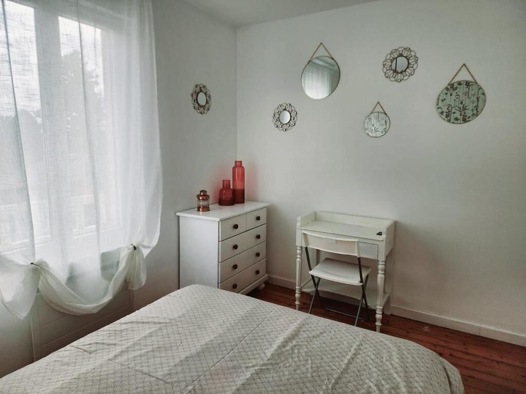 Une chambre à coucher comprenant un lit, une commode blanche, un bureau et des miroirs décoratifs fixés au mur.