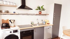 Eine kompakte Küche mit Waschmaschine, Backofen, Geschirrspüler und Spüle.