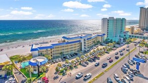 Een hotel met zwembad, parkeerplaats en uitzicht op strand en zee.
