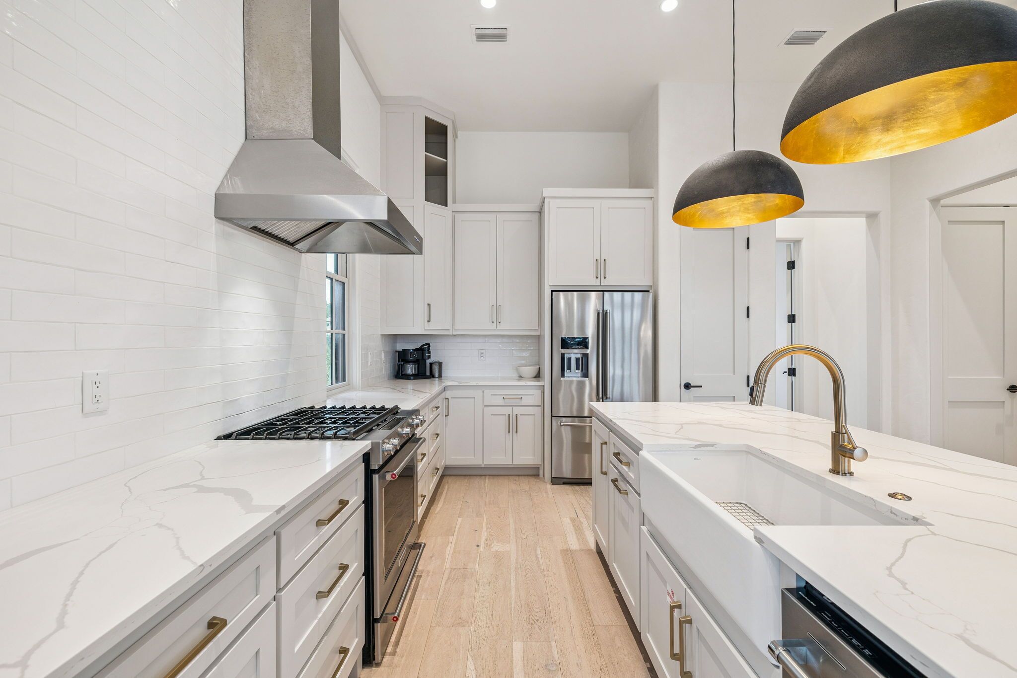 A modern kitchen with white cabinetry, stainless steel appliances, and a marble countertop.