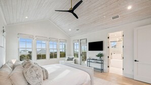 A spacious bedroom with a large bed, multiple windows, a ceiling fan, and a view of the outdoors. - Stylish Laid-Back Escape: Community Pool, 6 Bikes, & Spacious 3 Story Layout (Seagrove Beach)