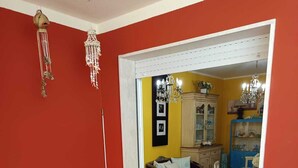 Un soggiorno con un divano, un tavolo da pranzo con un vaso di fiori e vista su una sala da pranzo con un lampadario.