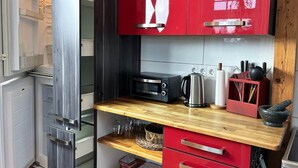 Une cuisine compacte équipée d’un four à micro-ondes, d’un grille-pain et d’une machine à café, le tout posé sur un plan de travail en bois.