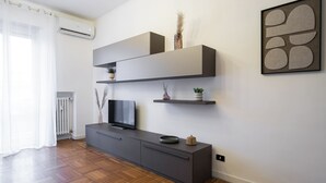 Un salon moderne avec un téléviseur à écran plat, une console grise et des étagères décoratives.