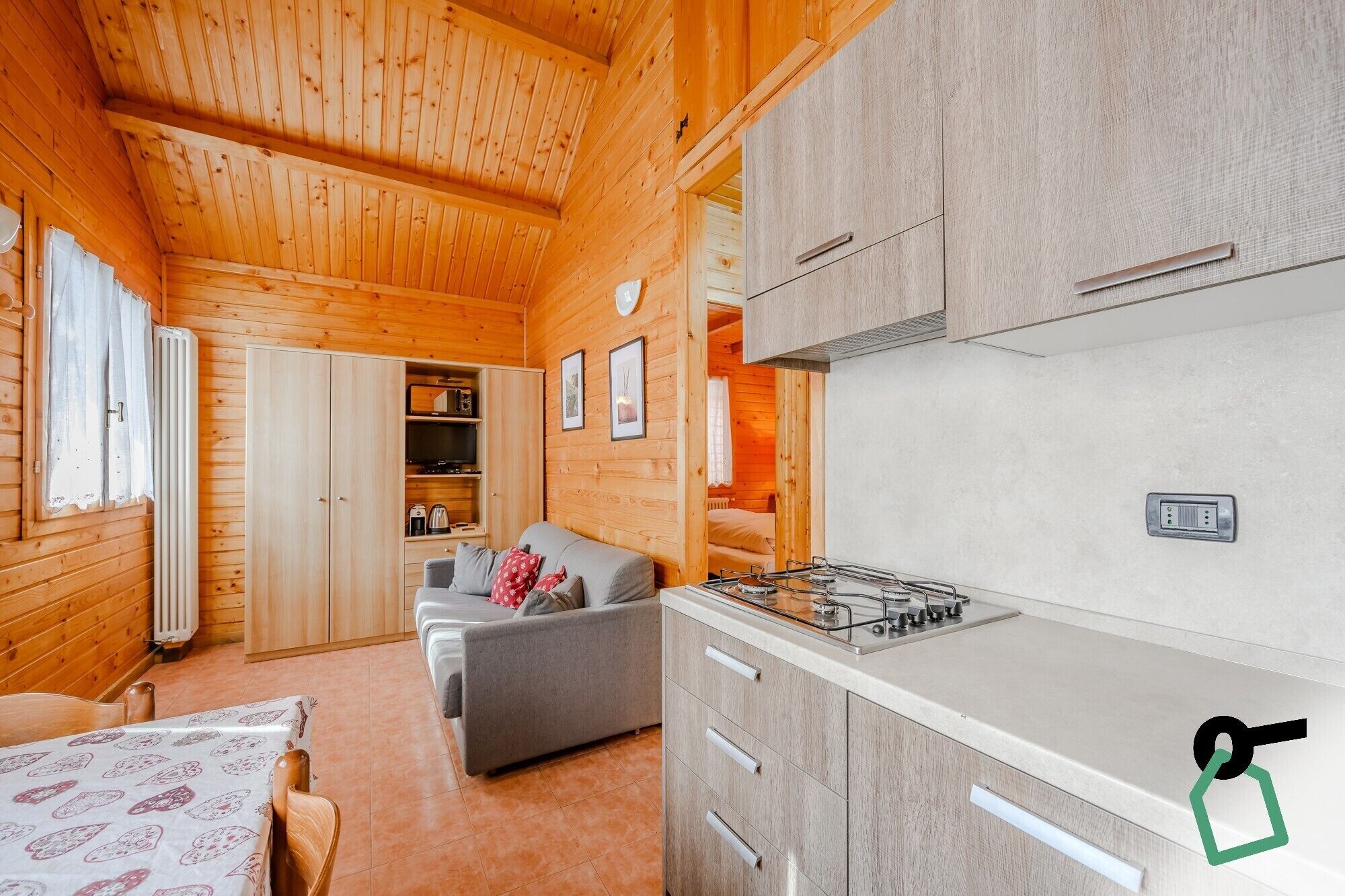 A cozy cabin interior with wooden walls, a kitchenette, a sofa, and a dining area.