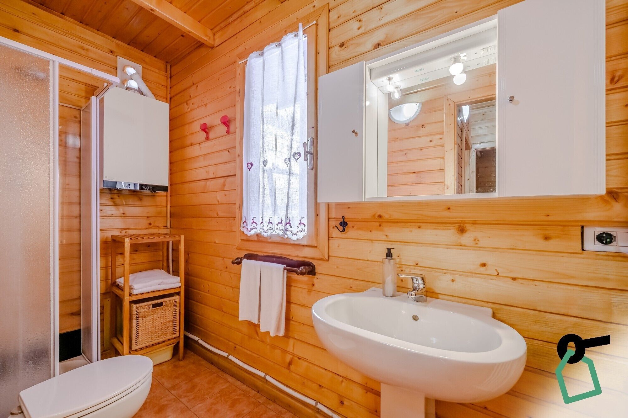 A wooden cabin bathroom with a toilet, sink, and a mirror above the sink.