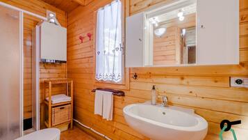 A wooden cabin bathroom with a toilet, sink, and a mirror above the sink.