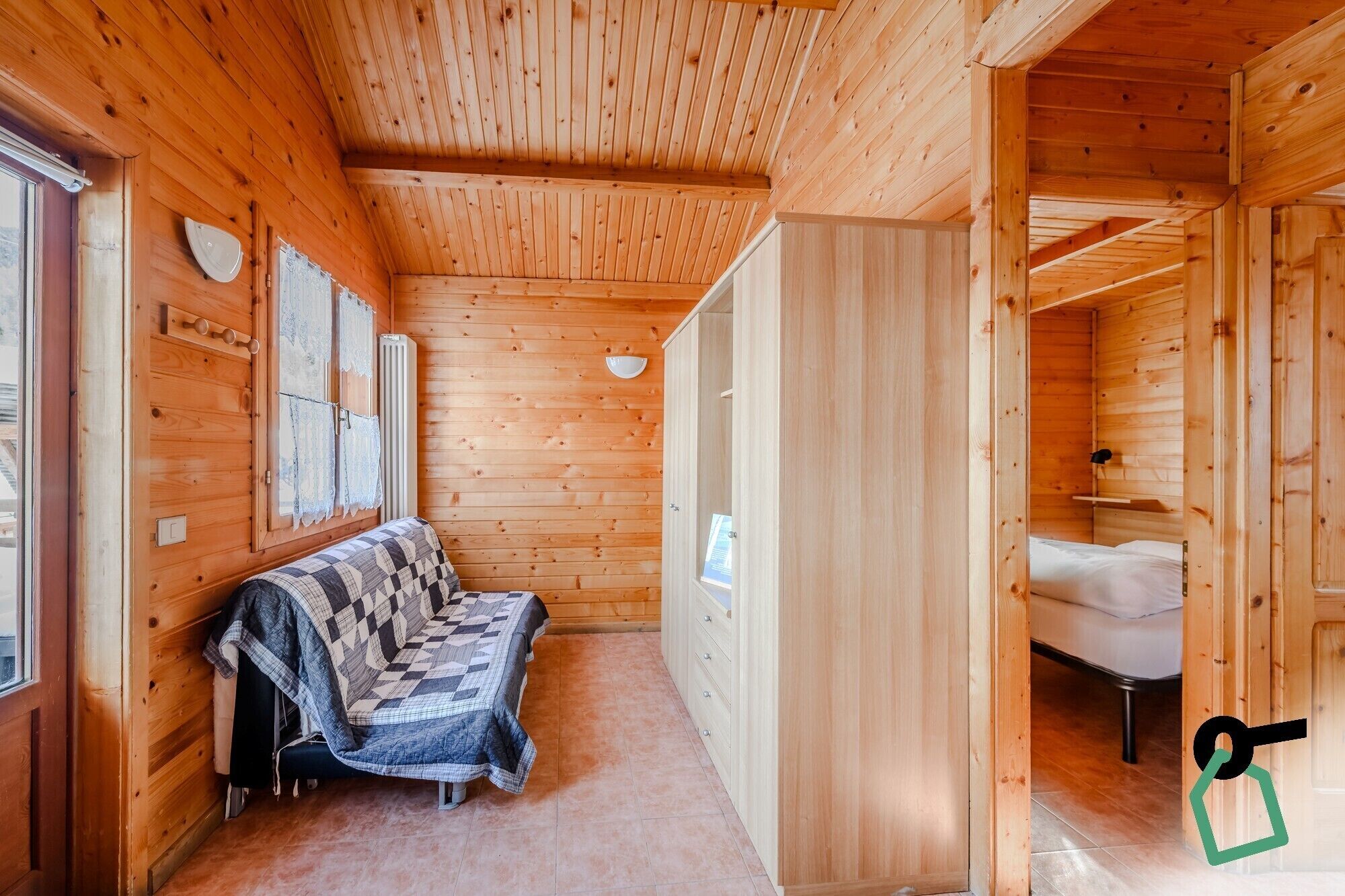 L'intérieur d'un chalet en bois, avec un canapé, un lit et une salle de bain.