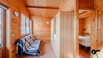 L'intérieur d'un chalet en bois, avec un canapé, un lit et une salle de bain.