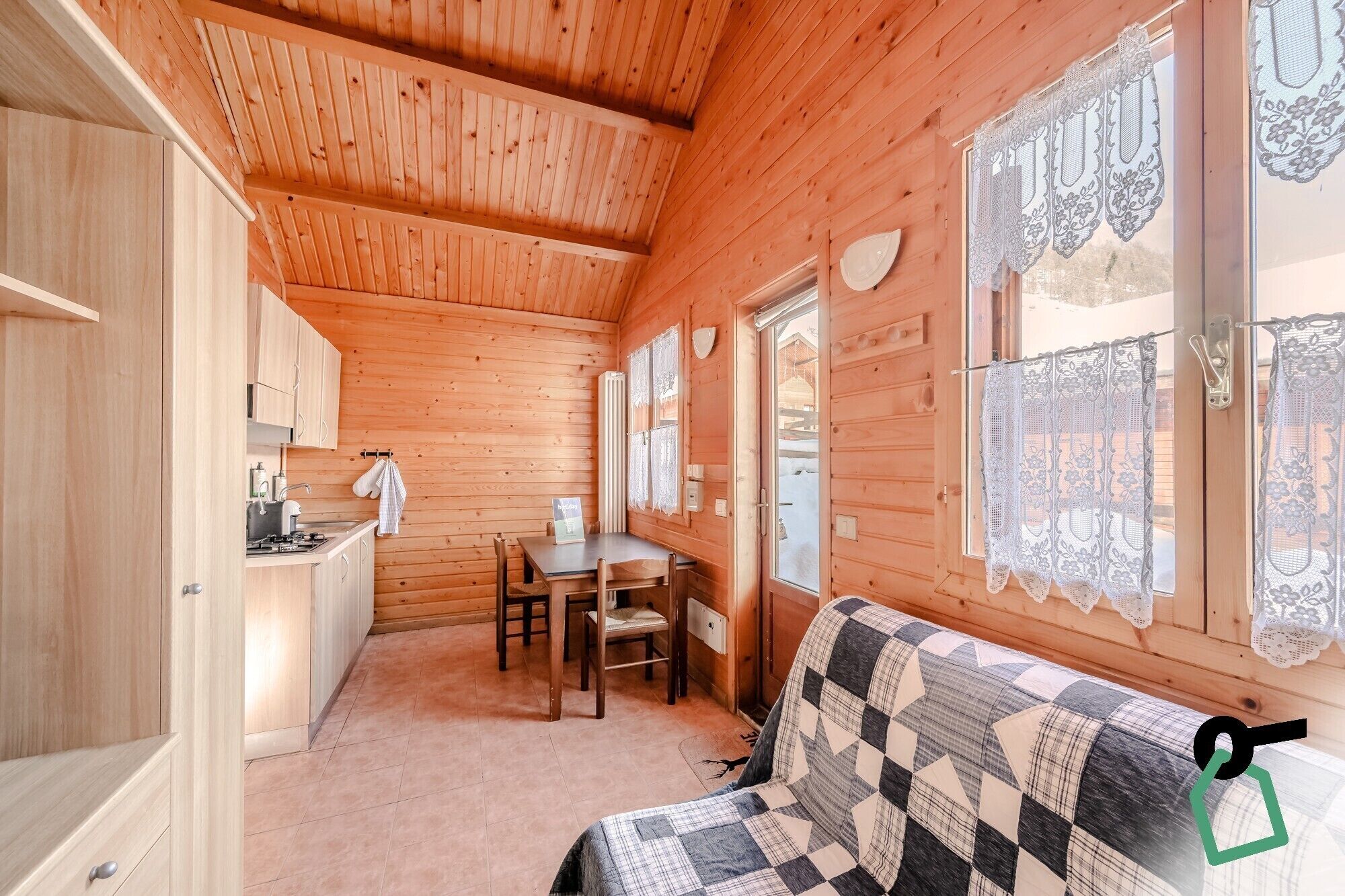 A cozy cabin interior with wooden walls, a dining area, and a sofa.