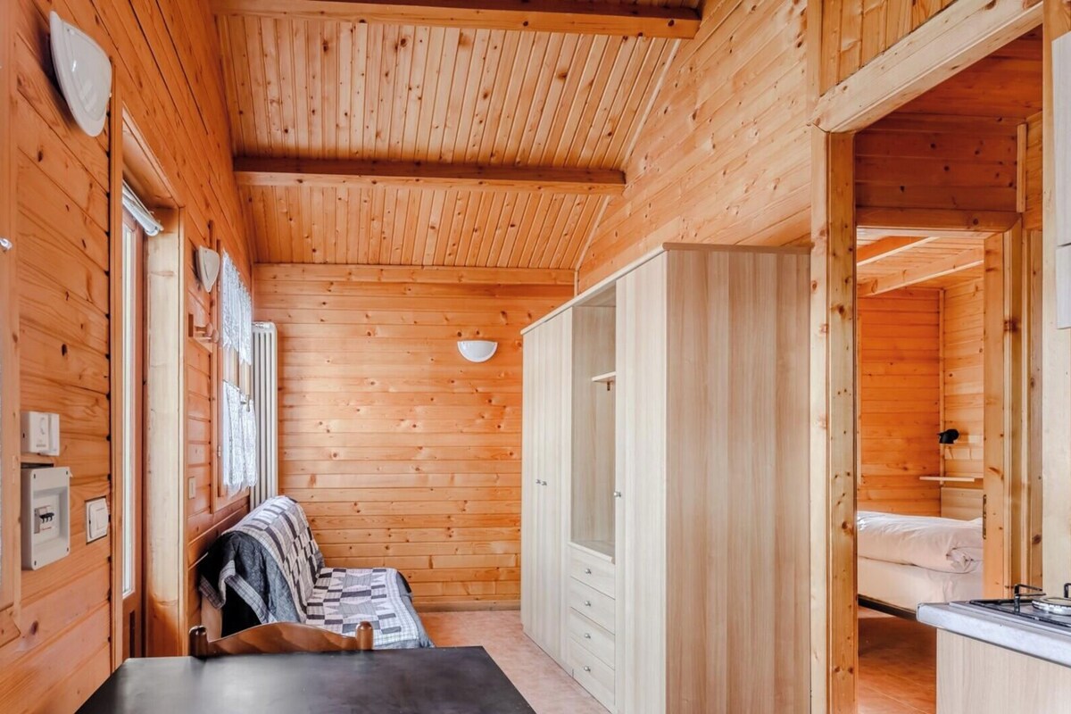 Ein Holzblockhaus-Interieur mit einem Bett, einem Tisch und einer Küchenzeile.