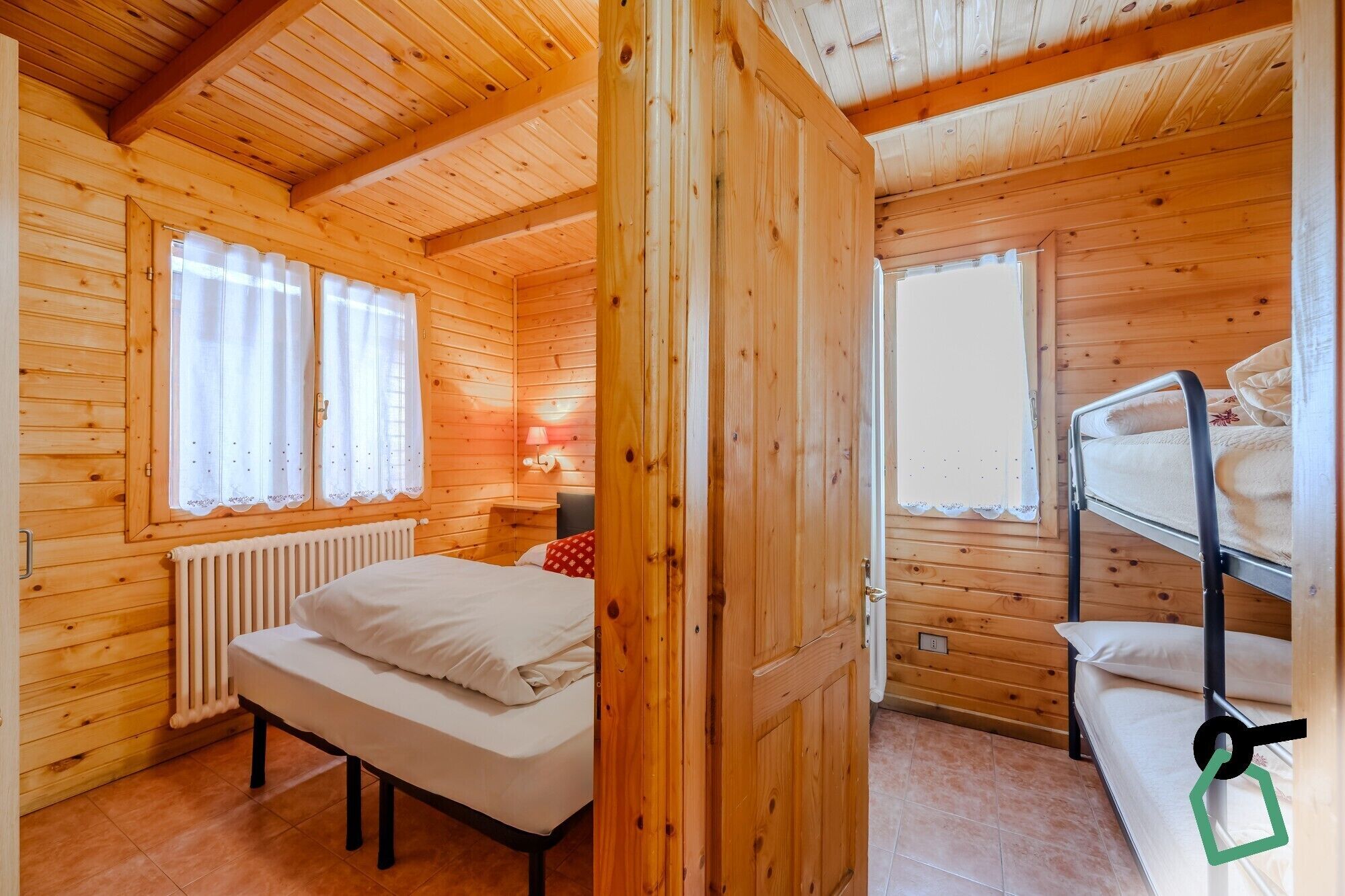 Una habitación de cabaña de madera con una cama litera, una cama individual y un radiador.