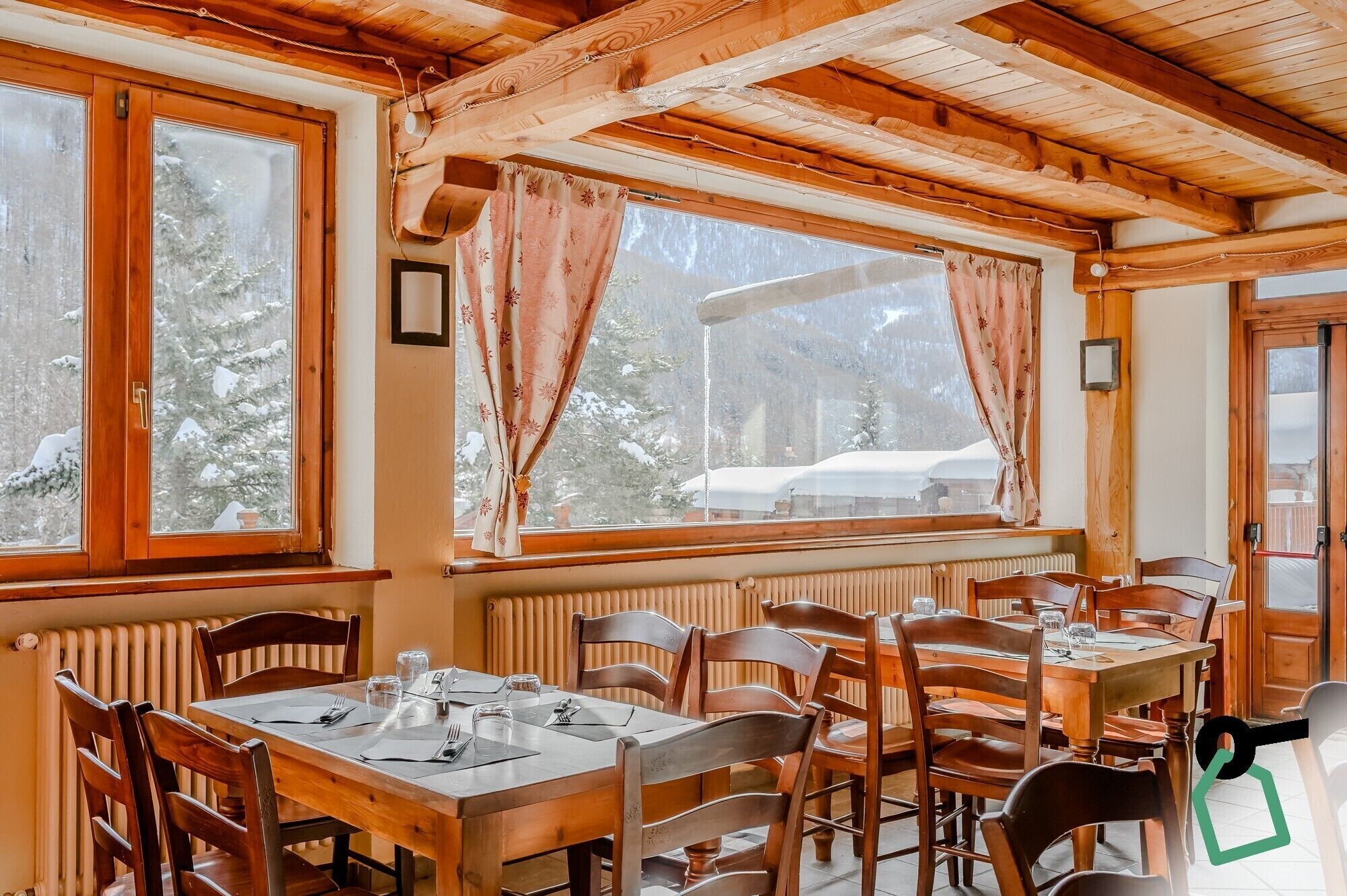 Un intérieur en bois comprenant un coin repas, de grandes fenêtres et une vue sur des arbres couverts de neige.