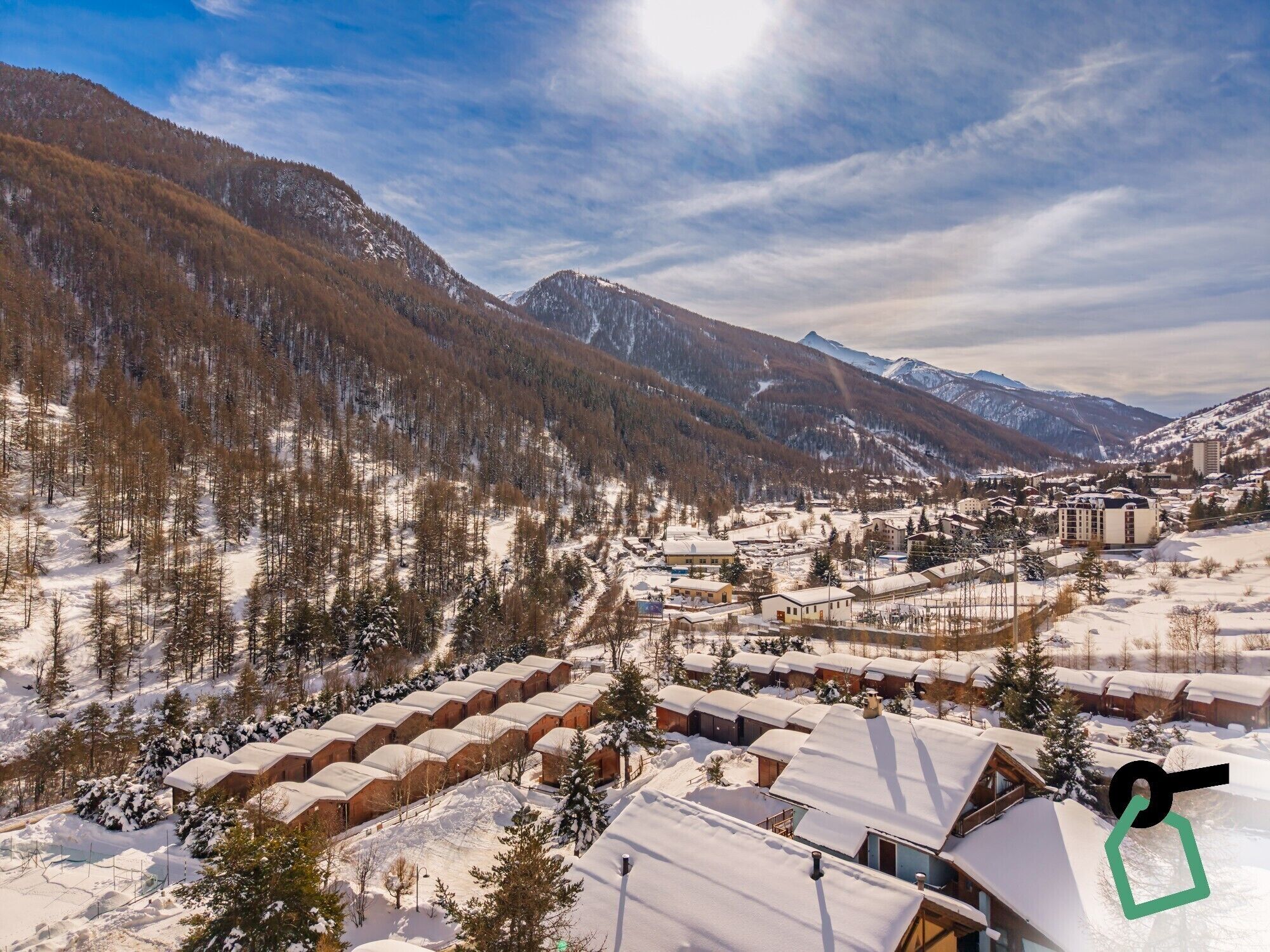 Un pueblo cubierto de nieve con edificios de estilo chalete y vistas de las montañas circundantes.