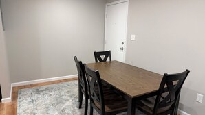 A dining area with a rectangular wooden table surrounded by six chairs, a patterned rug, and a white door. - Relaxing Modern 3BR Condo (Harrisburg)