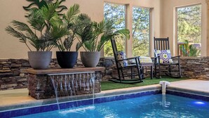 Ein Poolbereich mit Wasserfall, Kübelpflanzen und Sitzgelegenheiten am Pool.