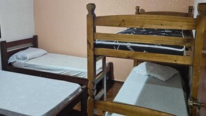 Une chambre de dortoir avec des lits superposés, un ventilateur de plafond et un revêtement de sol carrelé.