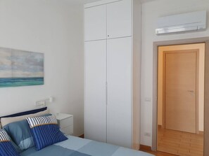 A bedroom with a bed, a nightstand, a wardrobe, and a door. - Charming three-room apartment 100m from the beaches (Imperia)
