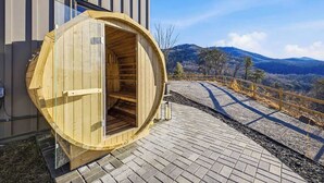 Una sauna de madera adosada a un edificio con vistas a montañas.