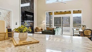 Una cocina amplia con una isla grande, un comedor con mesa y sillas, y una sala de estar con sofá y televisor.