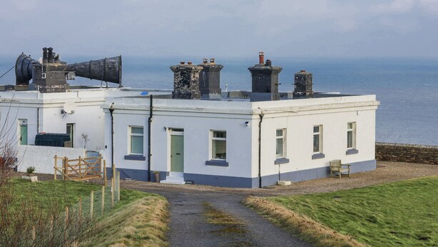 Ein Küstenhaus mit weißer Fassade, mehreren Schornsteinen und freiem Blick auf das Meer.