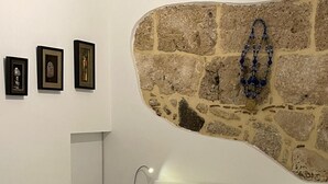 Een moderne slaapkamer met een stenen muur, een bed met beddengoed met een patroon en drie ingelijste kunstwerken aan de muur.
