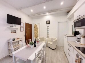 A compact kitchen with a microwave, oven, and a small dining area with a table and chairs. - Protea house 1 - Alghero (Alghero)