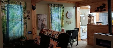 Un acogedor interior de cabaña con techo de madera, chimenea, comedor y decoración temática de bosque.