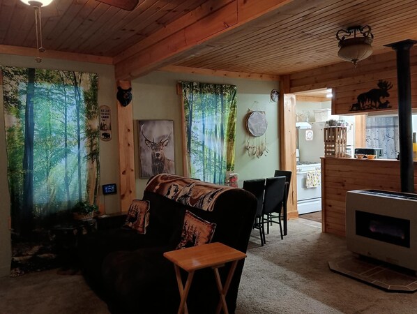 Un acogedor interior de cabaña con techo de madera, chimenea, comedor y decoración temática de bosque.