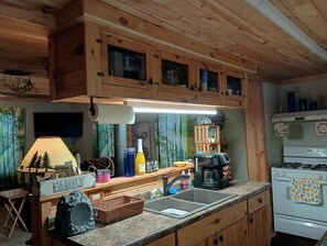 Una cocina con armarios de madera, un fregadero, una estufa y varios utensilios de cocina.
