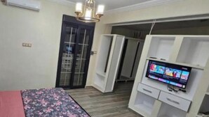 A bedroom with a bed, a TV, a wardrobe, and a door leading to another room. - Prestige Apartment & 24h Security (Ouled Fayet)