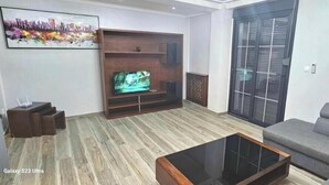 A living room with a Galaxy S23 Ultra TV, a grey sofa, and a wooden coffee table. - Prestige Apartment & 24h Security (Ouled Fayet)