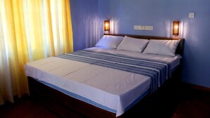 A hotel room with a large bed, two wall-mounted lamps, and a window with curtains. - lavish eco jungle (Weerawila)
