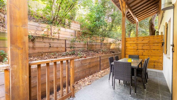 A patio area with a wooden fence, a table with chairs, and a pergola. - Apartment Near Plage Moutchic Lake (Lacanau)