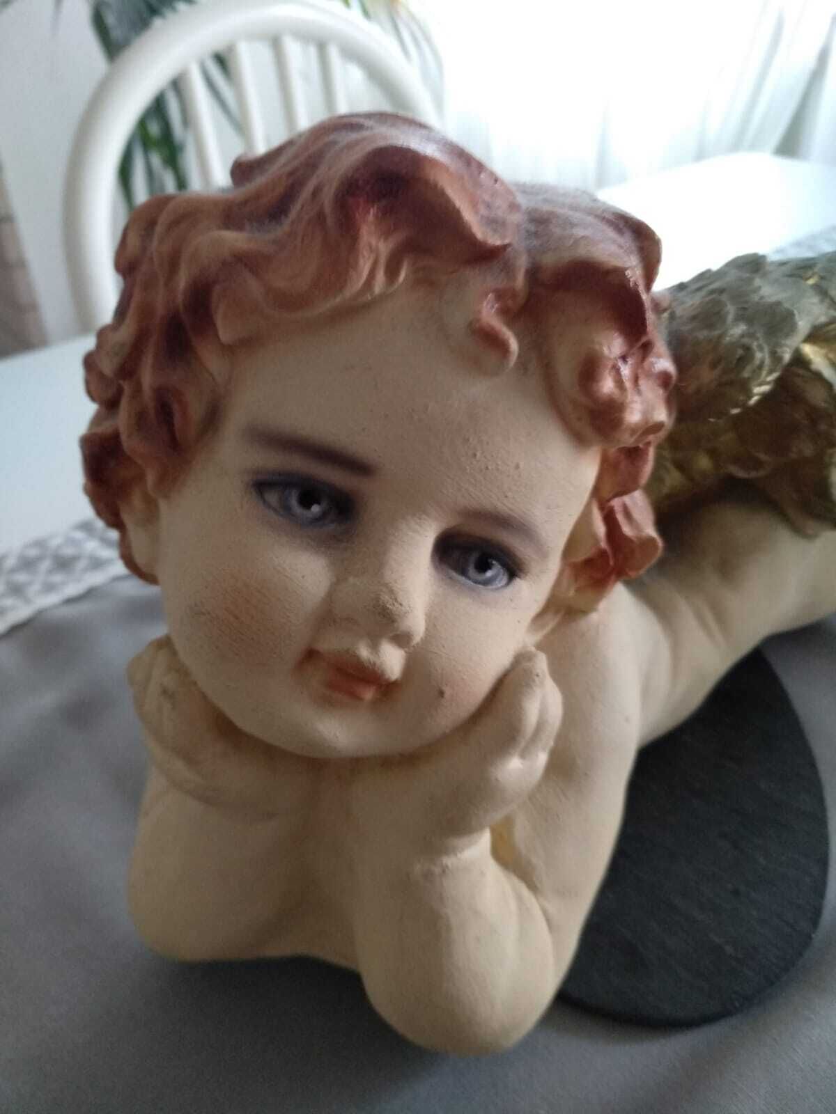 Una estatua de un ángel con rizos, sobre una superficie oscura.