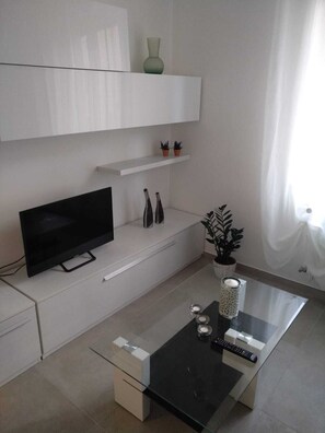 A modern living room with a flat-screen TV, a glass coffee table, and minimalist decor. - The Angel B&B, an 80-square-meter apartment located 200 meters from the ocean. (Porto Potenza Picena)