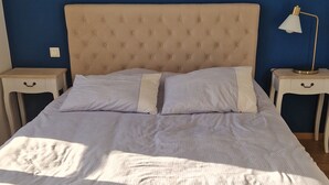 Ein Bett mit einer gepolsterten Kopfteil, zwei Nachttische mit Lampen und ein Holzboden.