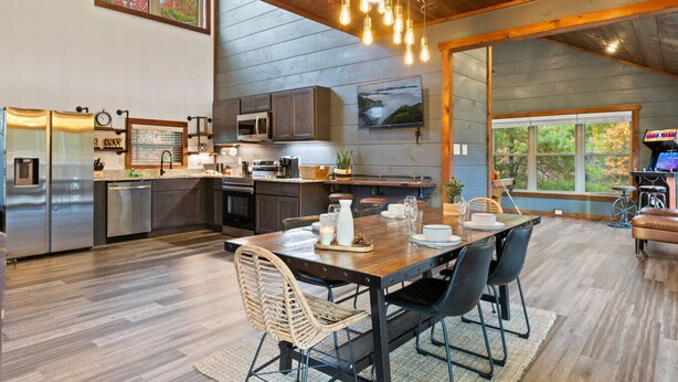 Een moderne keuken met roestvrijstalen apparatuur, een eethoek met een houten tafel en stoelen, en een groot raam met uitzicht op de omgeving.