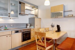A modern kitchen with built-in appliances, a dining area with wooden furniture, and a microwave above the counter. - Apartment 'Tannenliebe' with Private Terrace, Shared Garden and Wi-Fi (Feldberg-Altglashütten)