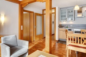 A modern kitchen with wooden cabinets, a dining table, and a chair. - Apartment 'Tannenliebe' with Private Terrace, Shared Garden and Wi-Fi (Feldberg-Altglashütten)